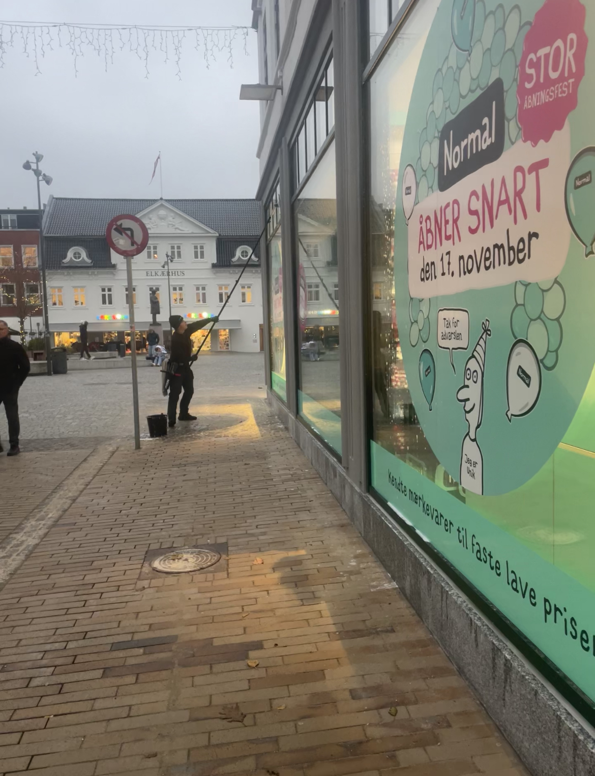 Medarbejder vasker høje vinduer med rentvandsanlæg og teleskopstang